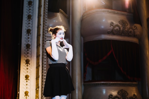 Shy female mime artist performing on stage in the auditorium