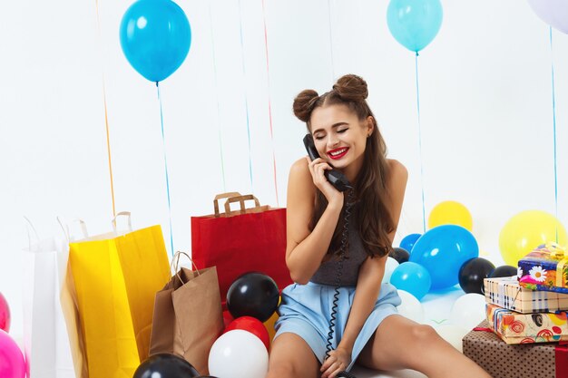 Shy and pretty girl sitting with birthday gifts receiving wishes