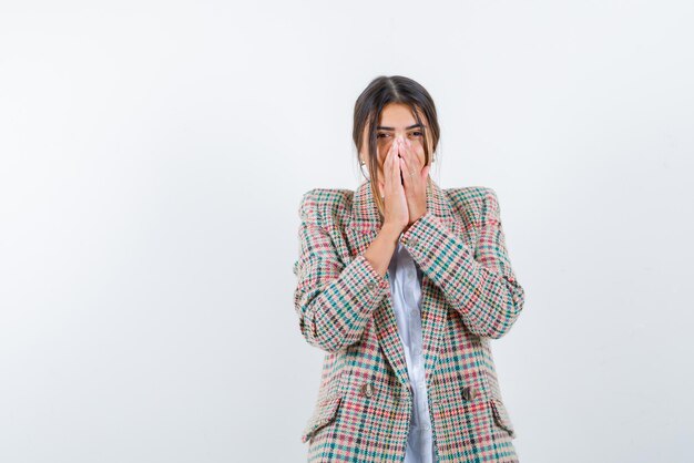 Shy young woman covering her mouth with hands on white background