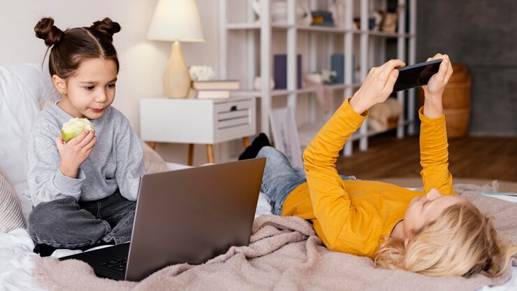 Free Photo siblings in bed watching video on laptop and mobile