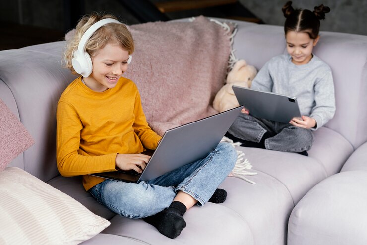 Free Photo siblings on couch with laptop