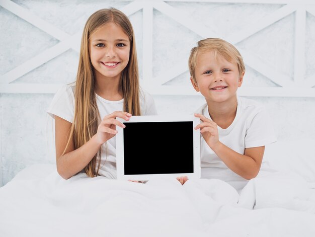 Siblings holding a tablet mock-up