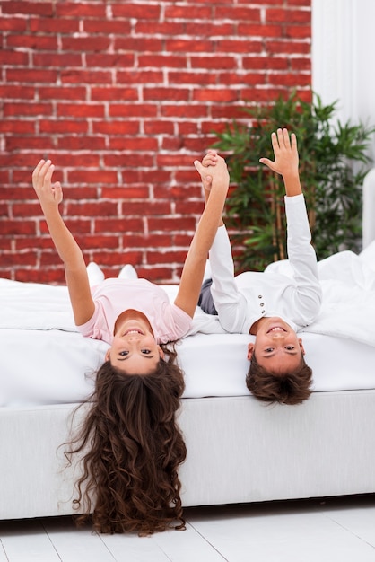 Free photo siblings at home laid in bed and holding hands