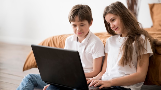 Siblings at home using laptop