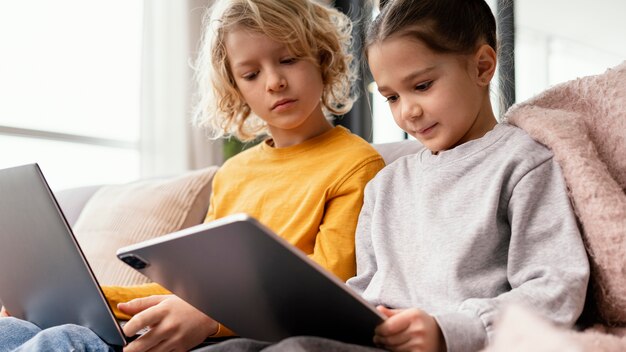 Siblings at home with devices