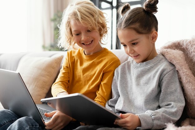 Siblings at home with devices