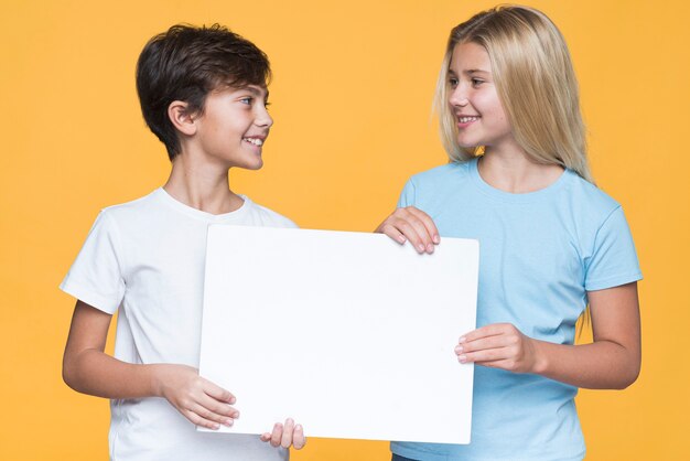 Siblings looking at each other while holding paper sheet