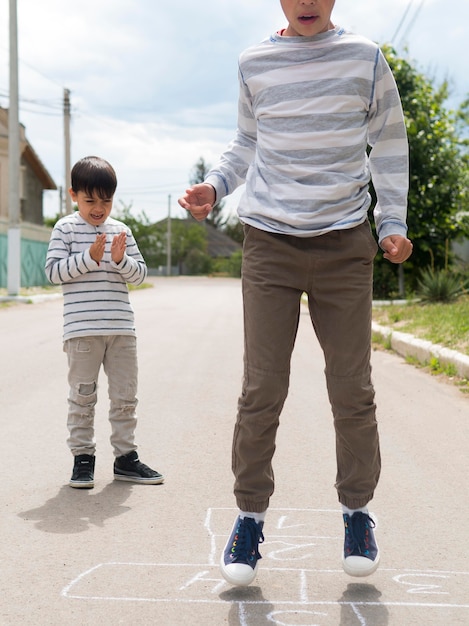 Siblings playing hopscotch with chalk