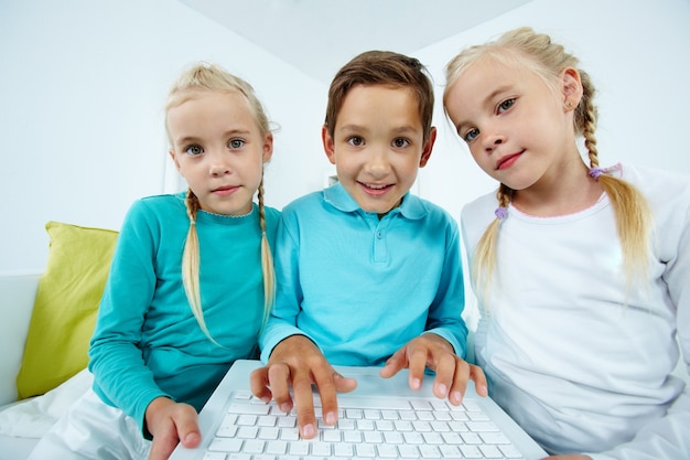 Free photo siblings sitting on the sofa with laptop