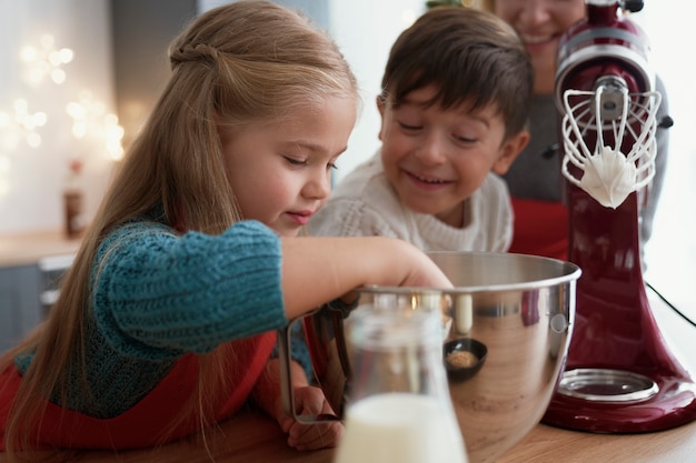 Siblings tasting sugar paste during baking with family