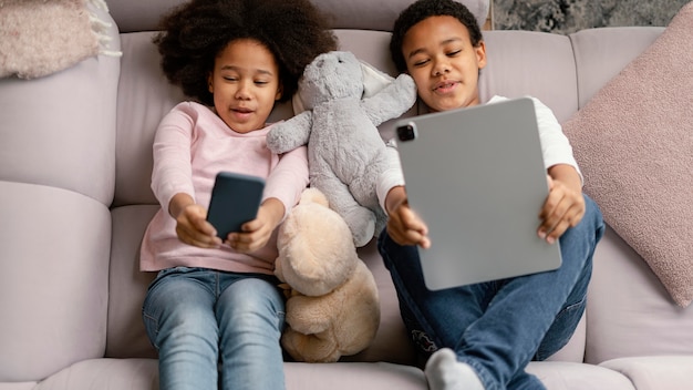 Siblings using tablet and mobile at home