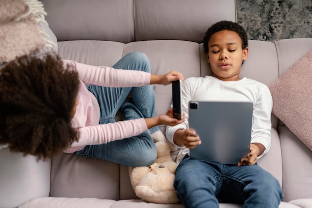 Siblings using tablet and mobile at home