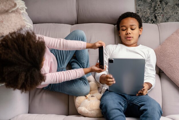 Siblings using tablet and mobile at home