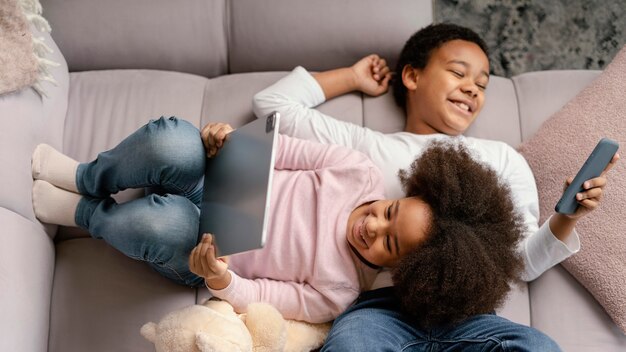 Siblings using tablet and mobile at home