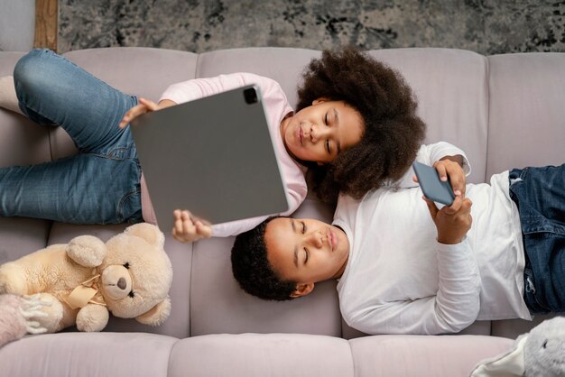 Siblings using tablet and mobile at home