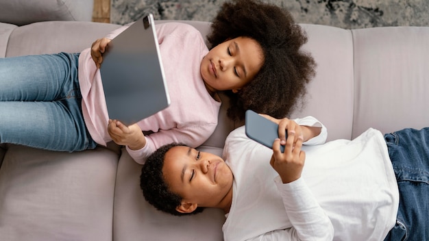 Siblings using tablet and mobile at home