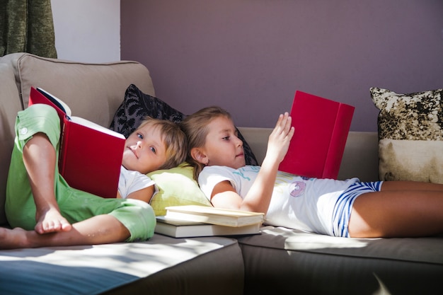 Siblings with books on sofa