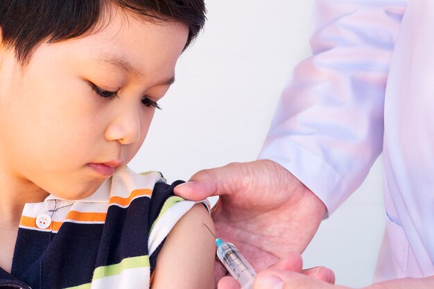 Sick Asian boy being treated by male doctor over white background