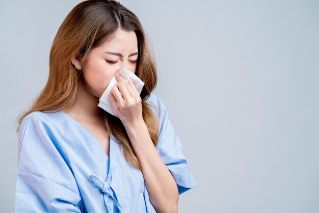 Sick asian female woman weather allergy sneeze and cough in hospital uniform health and illness ideas concept