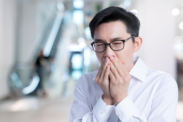 Sick asian glasses male adult cold and flu symptom hand close mouth shut with stressful and tension white background health ideas concept