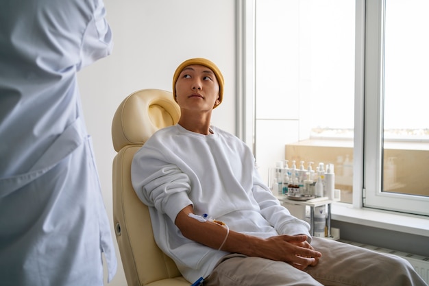 Sick asian man sitting on chair side view