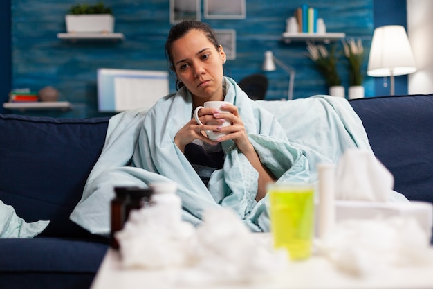 심한 감기와 독감으로 침대에 앉아 있는 백인 여자