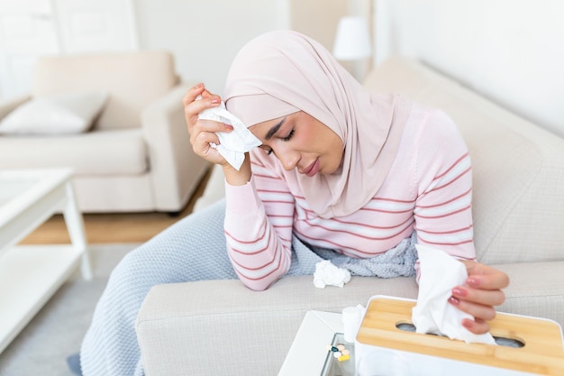 Sick day at home Young Arabic woman has runny and common cold Cough Closeup Of Beautiful Young Woman with hijab Caught Cold Or Flu Illness
