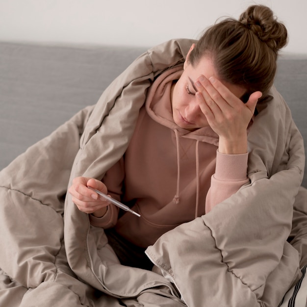 Free photo sick female person looking at the thermometer