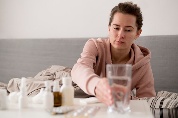 Sick female person reaching  for a glass of water