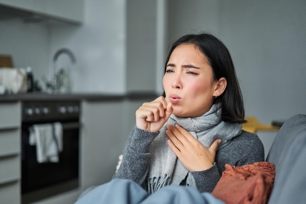 Foto gratuita una donna coreana malata che tossisce e si sente male facendo smorfie ha l'influenza tosse il raffreddore o l'influenza rimane