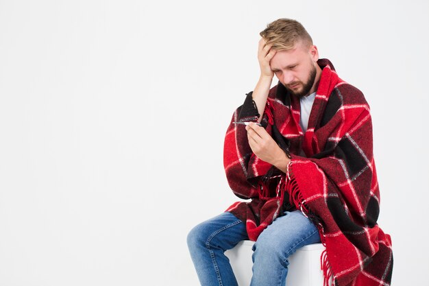 Sick man looking at thermometer 