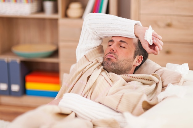 Sick man lying down on couch with high fever