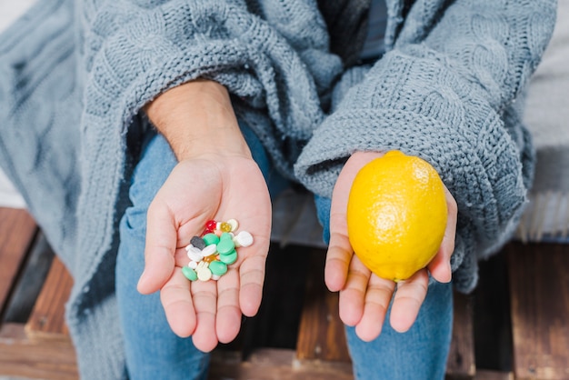 Foto gratuita la mano dell'uomo malato che mostra le pillole multicolori e il limone intero