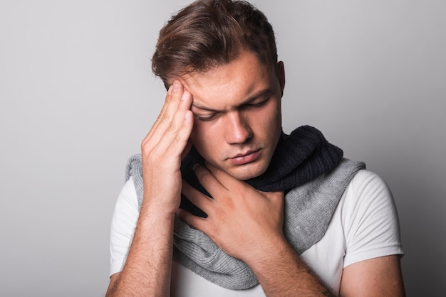 Sick man suffering from headache and cold against gray background