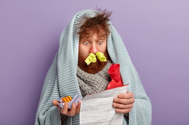 Foto gratuita uomo malato in vestiti caldi con pillole e sacca d'acqua