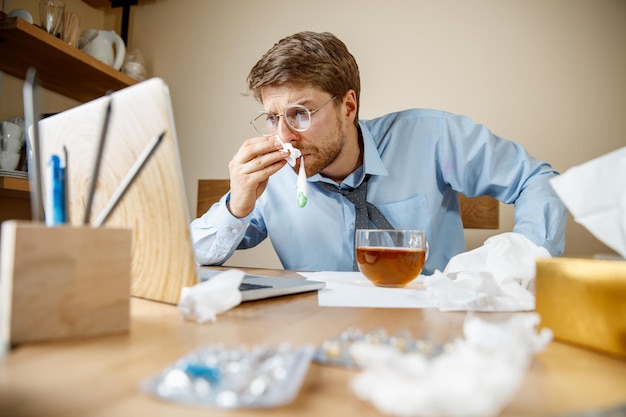 Sick man while working in office, businessman caught cold, seasonal flu.