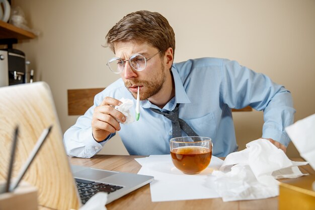 Sick man while working in office, businessman caught cold, seasonal flu.