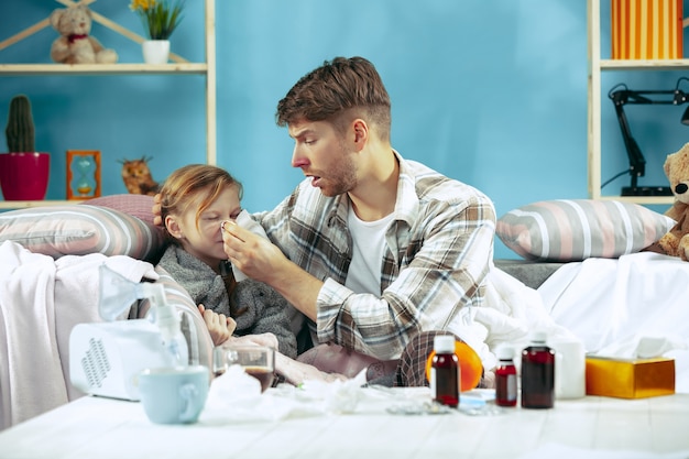 Uomo malato con la figlia a casa. trattamento domiciliare. combattere con una malattia. assistenza medica. insufficienza familiare. l'inverno, l'influenza, la salute, il dolore, la paternità, il concetto di relazione. relax a casa