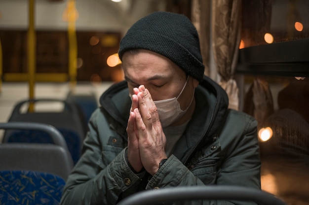 Foto gratuita uomo malato con la mascherina medica che prega nell'autobus