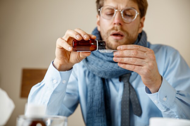 Sick man with medicinal mixture working in office