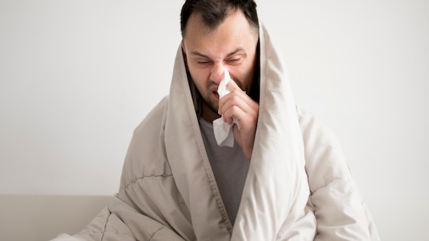 Free photo sick person wrapped in a blanket and having a runny nose