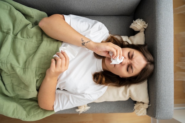 Free photo sick woman on couch at home top view