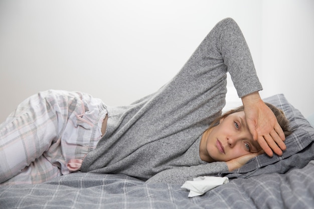 Sick woman feeling temperature, touching forehead with hand