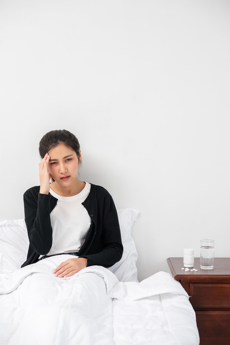 無料Photo 病気の女性は頭痛があり、手はベッドの上の彼女の頭に触れました。