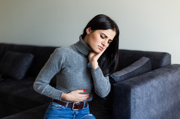 Sick woman having stomachache in the living room