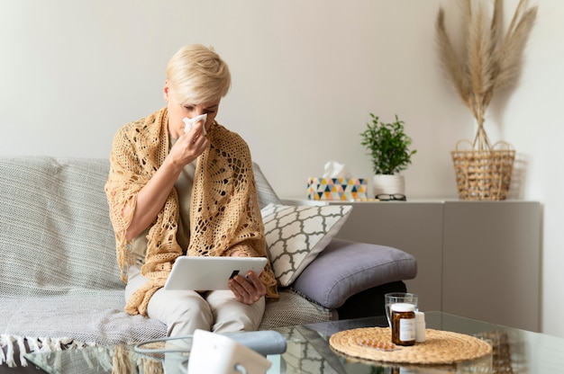 Sick woman holding tablet medium shot