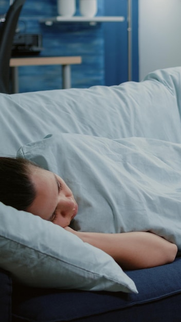 Foto gratuita donna malata sdraiata sul divano con una coperta che si sente fredda e presenta sintomi di virus. adulto con influenza stagionale che dorme, con farmaci sul tavolo. malato stanco con brividi e brividi