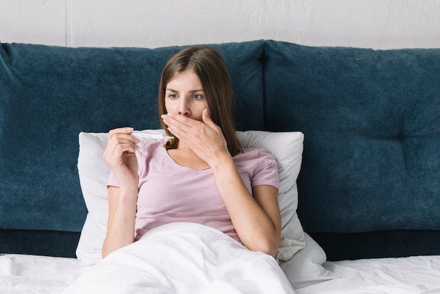 Free photo sick woman shocked by high temperature on thermometer