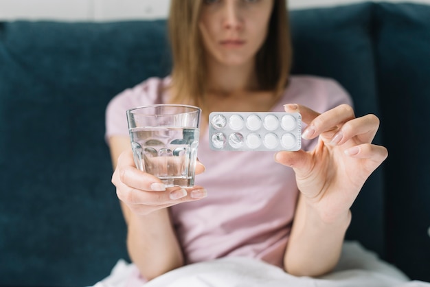 Foto gratuita blister della pillola della donna malata e bicchiere d'acqua