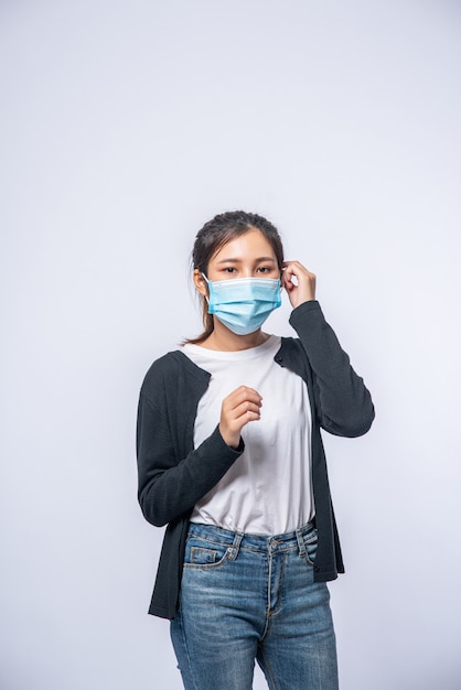 A sick woman with a headache wore a mask and placed a hand on her head.